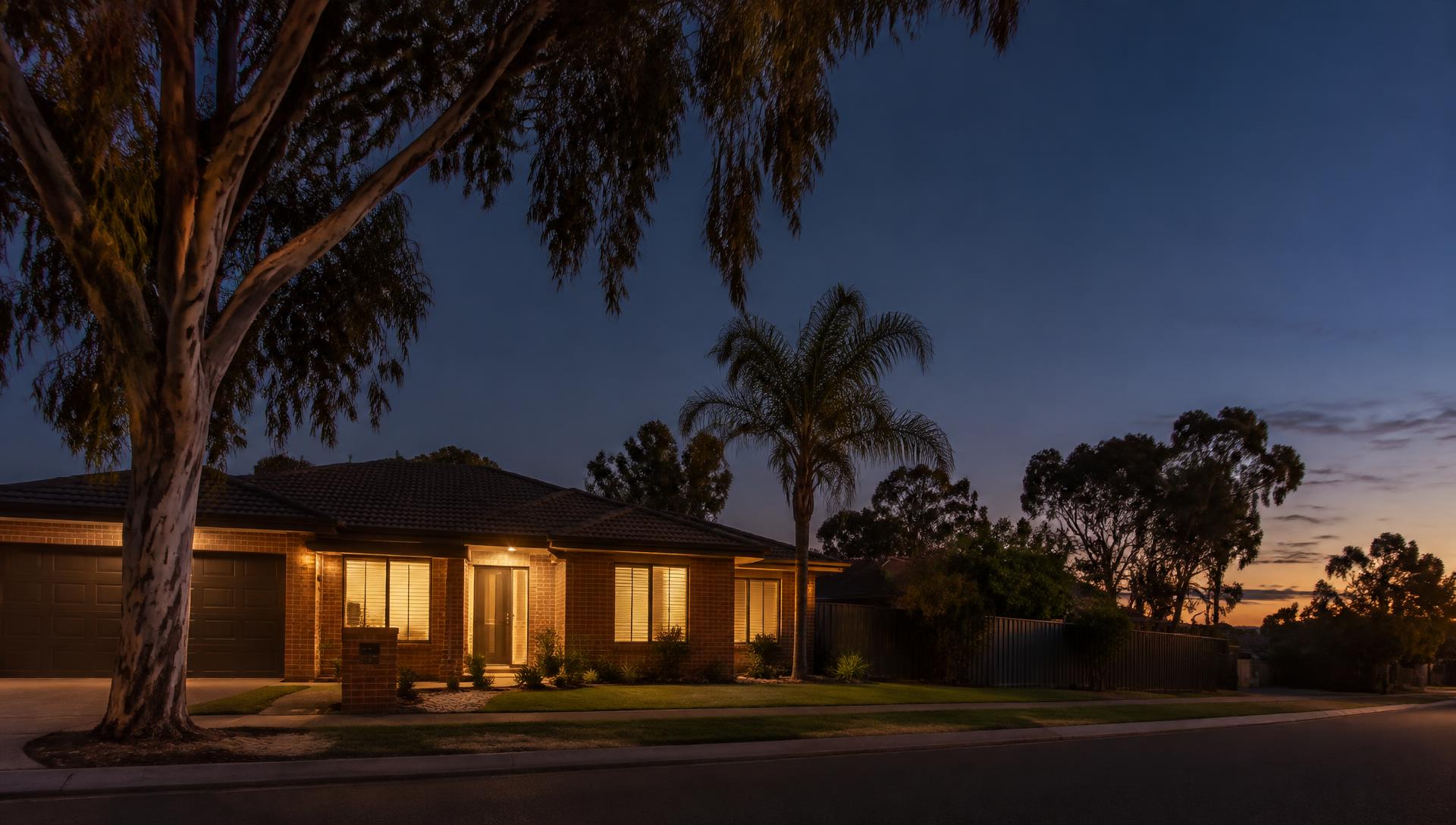 Brick veneer home at dusk with warm lights on inside